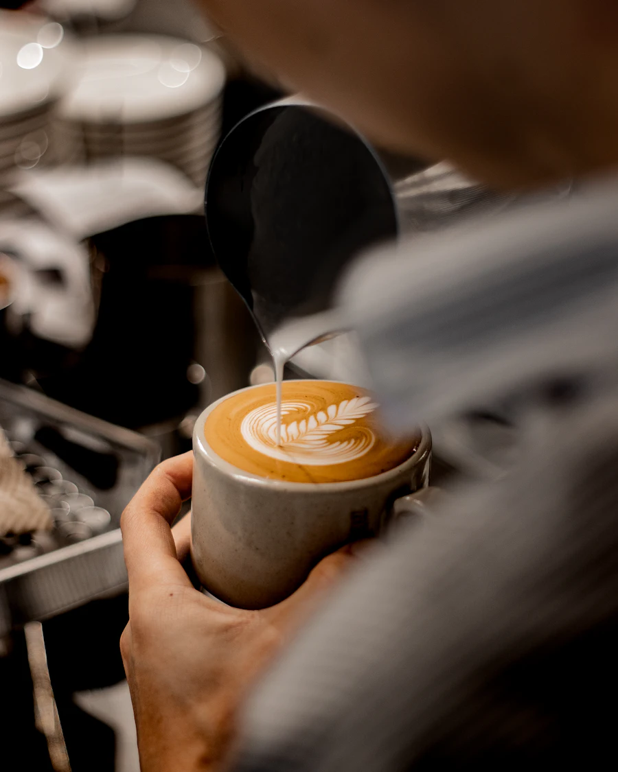 Barista pouring latte art into a ceramic cup