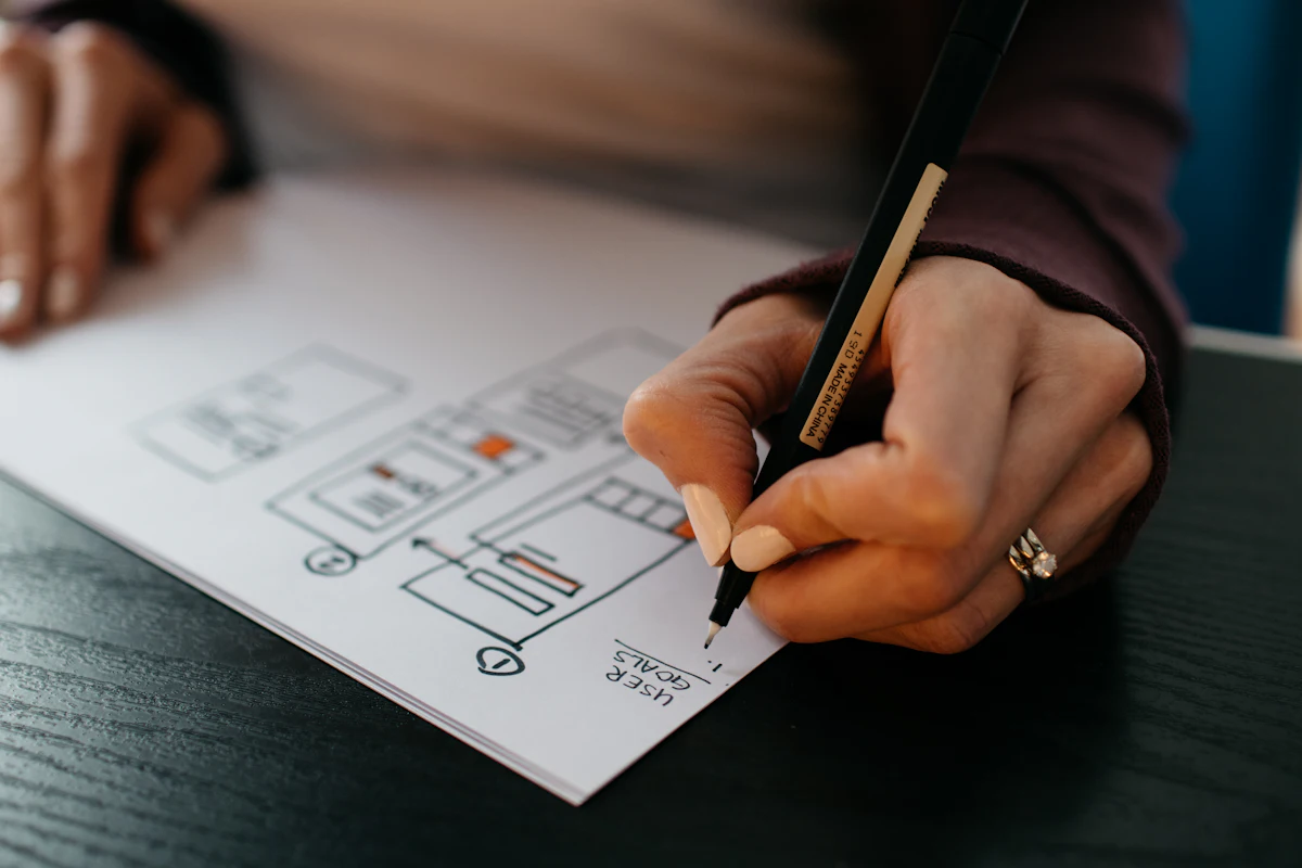 Hands sketching interface wireframes in pencil